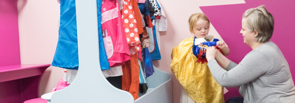 Photo of grandparent helping to get toddler into fancy dress.