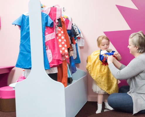 Photo of grandparent helping to get toddler into fancy dress.